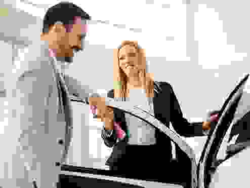 women and guy smiling looking at a car 